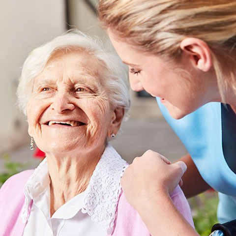 Happy elderly woman outside with attendant